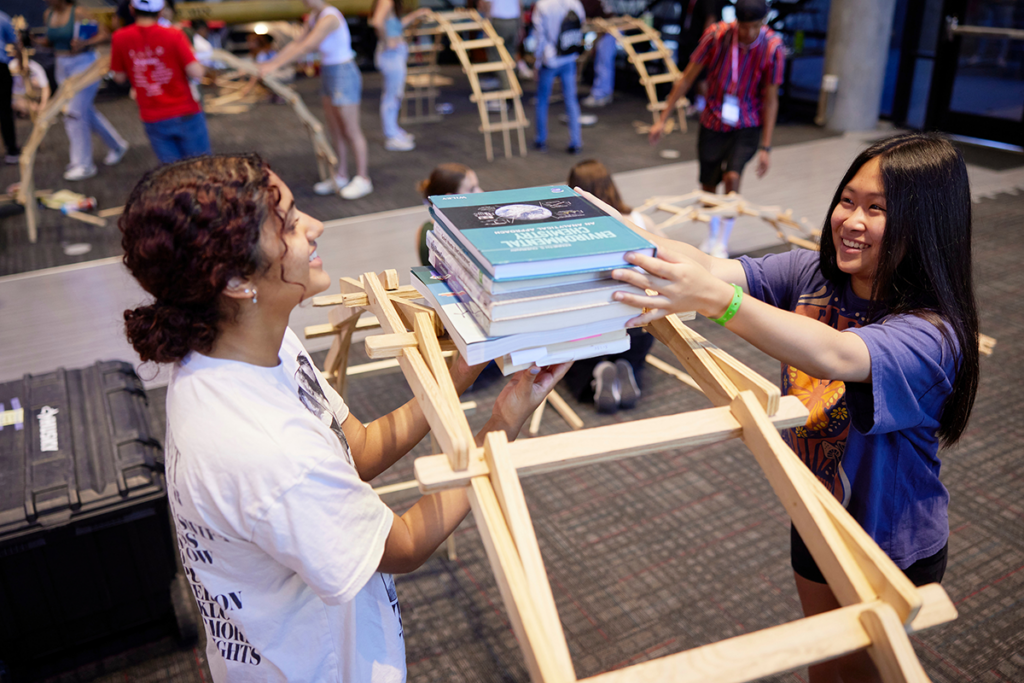 2 students balancing books on a bridge